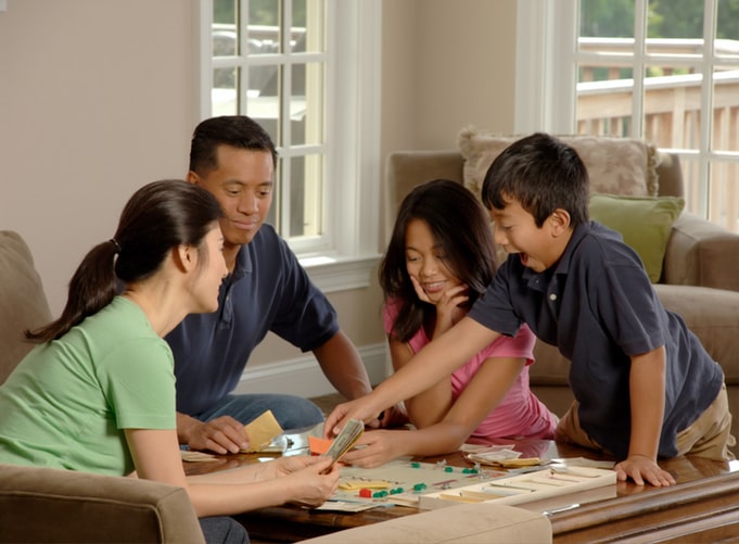 Family gatherd around a table playing a board game